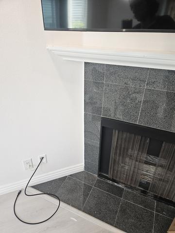 Flat-screen TV mounted above a marble fireplace with soundbar